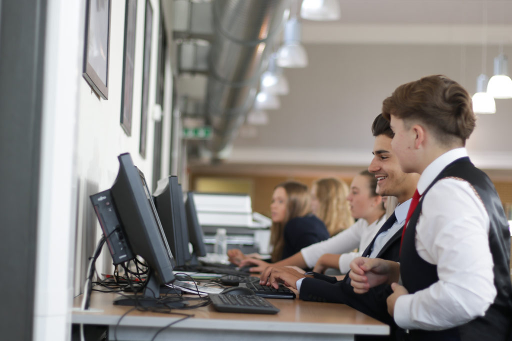 A small group of Post-16 Leigh Academy Longfield students sit together whilst working on computers.