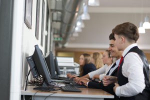A small group of Post-16 Leigh Academy Longfield students sit together whilst working on computers.