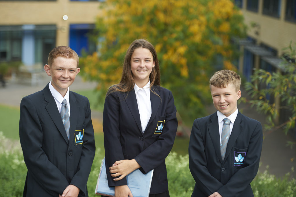 Three Leigh Academy Longfield students in uniform pose for the camera outside of the building.