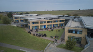 Photo of the outside of the Leigh Academy Longfield building, showing students walking around it.