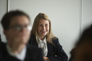 A male Leigh Academy Longfield student sits with a member of staff whilst looking at work together.