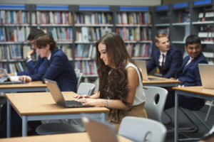 A sixth form student working on their laptop in the library