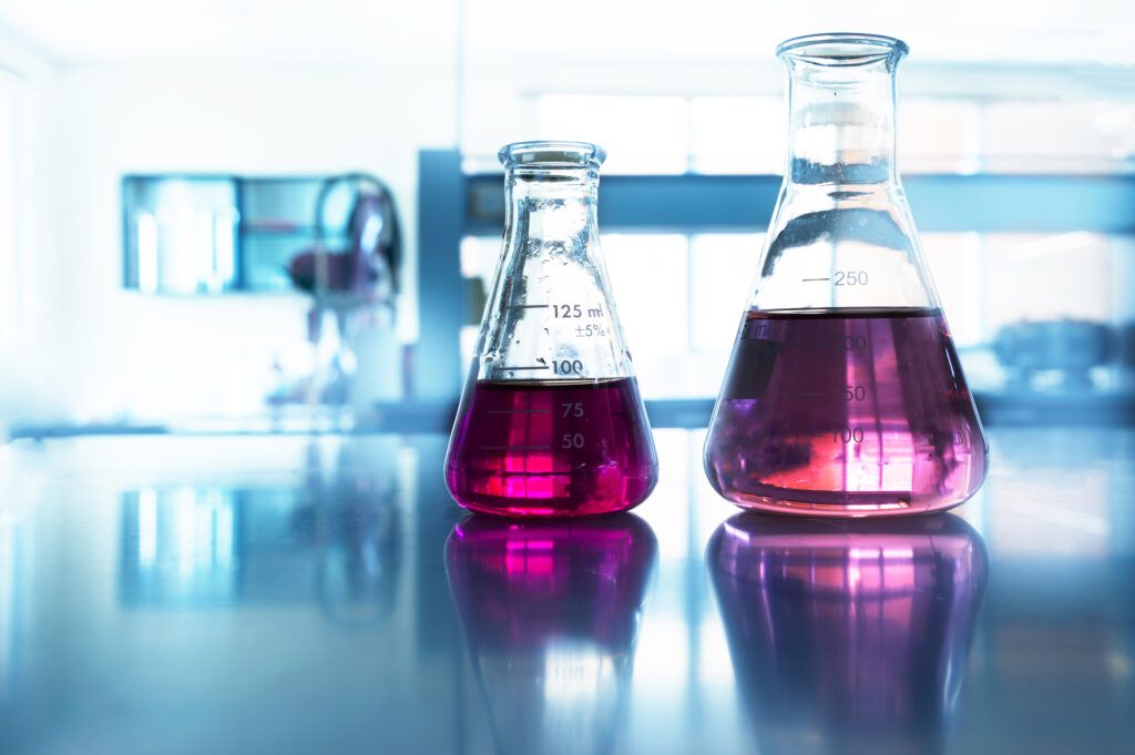 two glass flask with pink solution on the table in chemistry science blue laboratory background