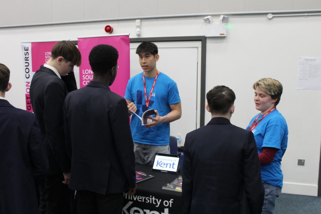 Students speaking to 2 people at a University of Kent stall
