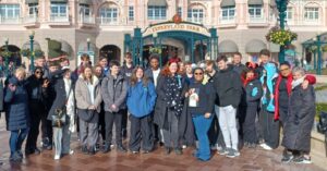 A group of students smiling for a photo in front of the Disneyland Paris entrance